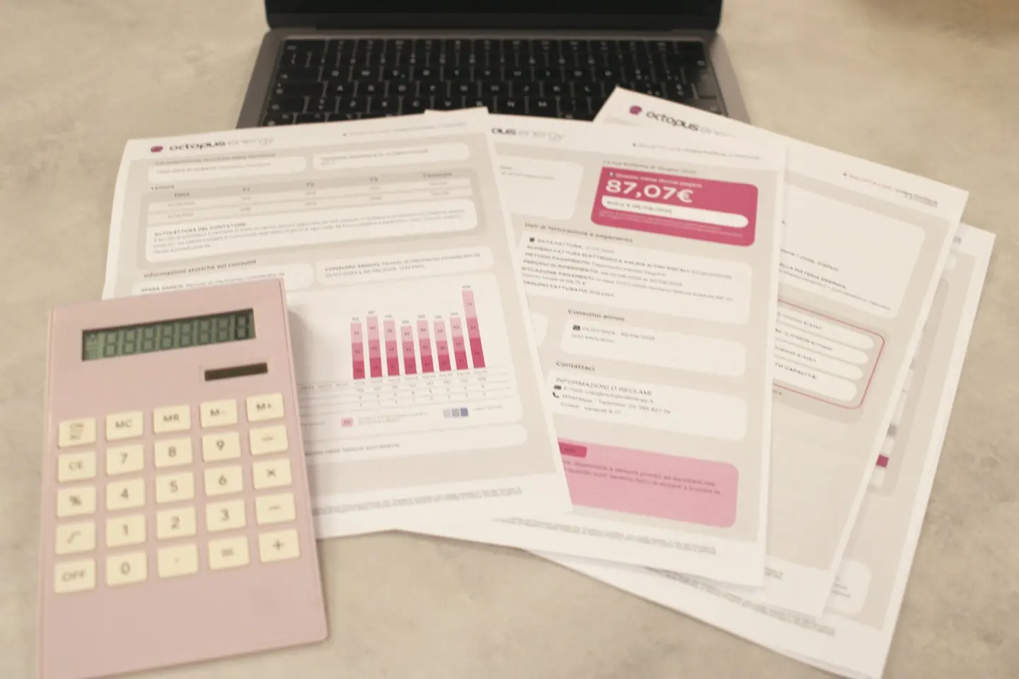 Factures papier, calculatrice rose et ordinateur portable sur un bureau