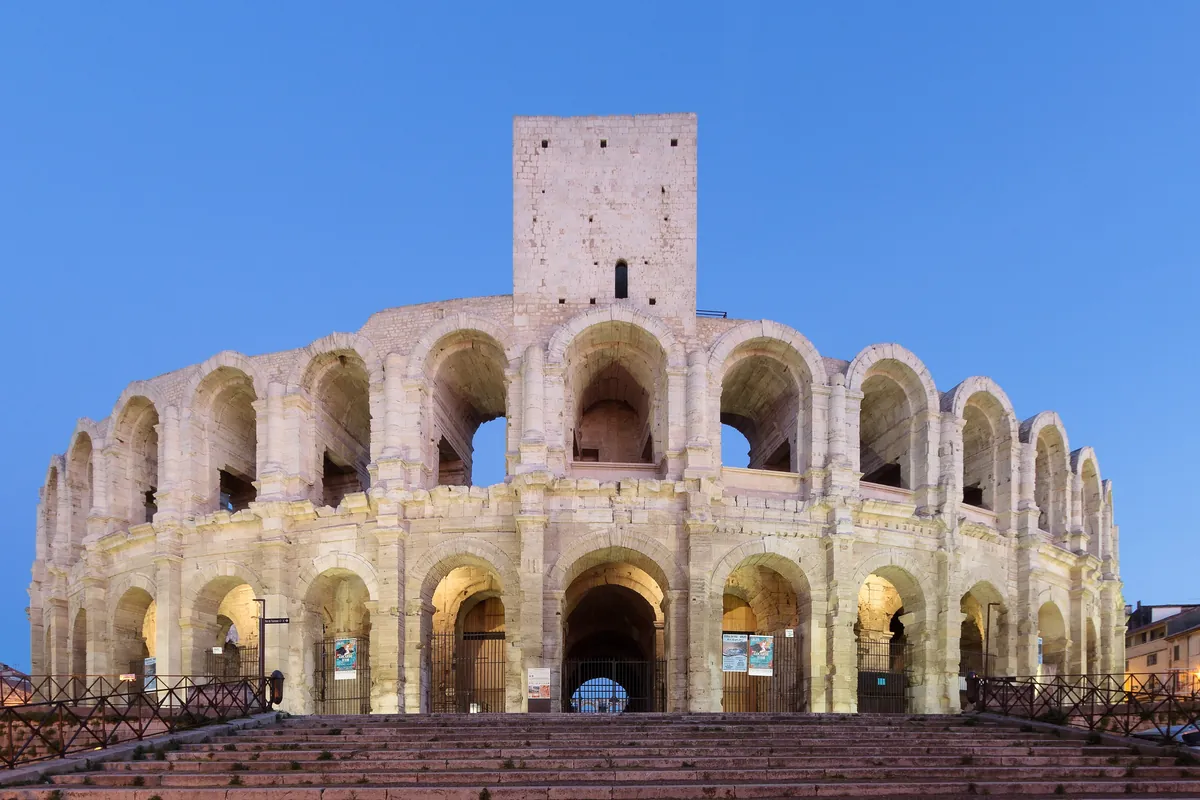 L’amphithéâtre romain d’Arles éclairé, à la tombée de la nuit