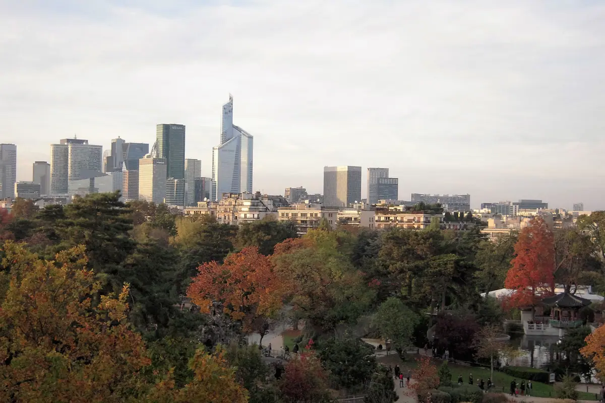 La silhouette des tours de La Défense derrière les arbres d’un parc, à l’automne